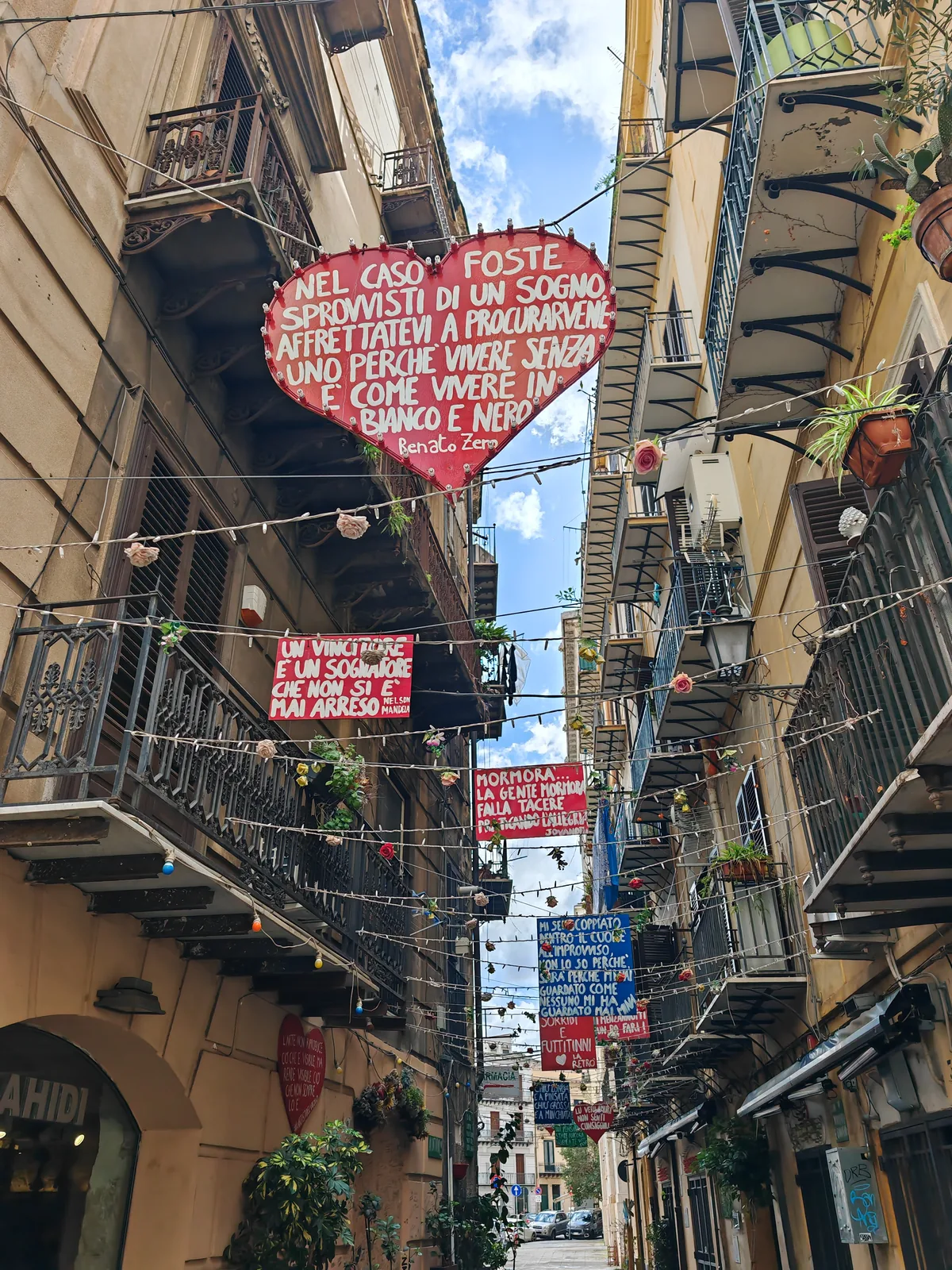 What to See in Palermo in One Day: A Walking Itinerary Through the Old Town 8 An old-town alley in Palermo decorated with signs and poems